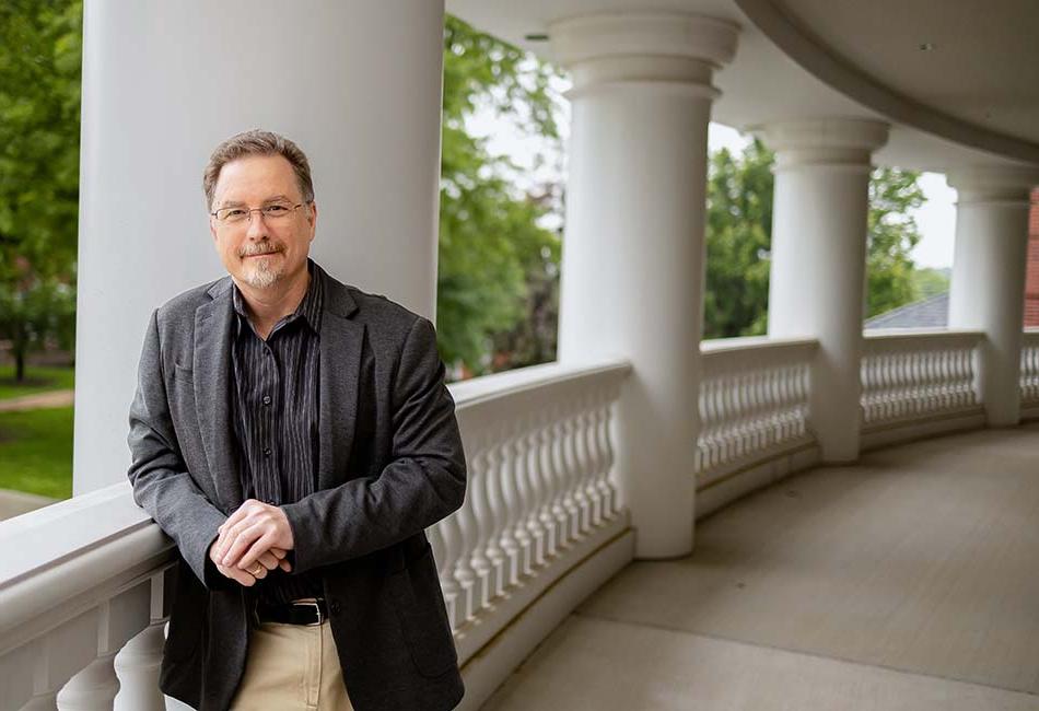 丹尼尔Schwabauer, 英语助理教授, 靠在坎宁安中心的阳台栏杆上，俯瞰着校园购物中心.
